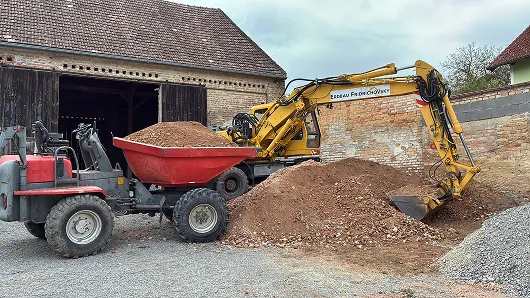 Dumper und Bagger beim Umschlag von Schüttgut