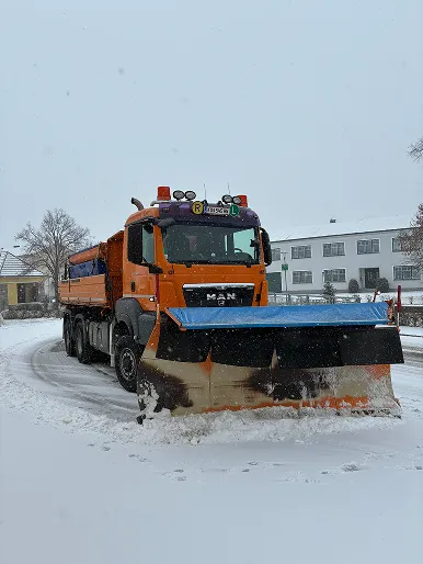 MAN LKW mit Schneepflug im Winterdiensteinsatz im Ort